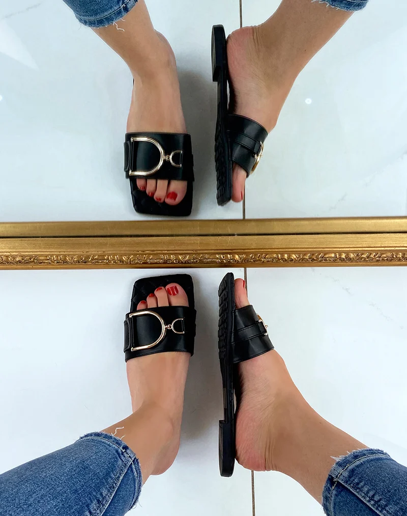Mules plates noires à détail doré asymétrique